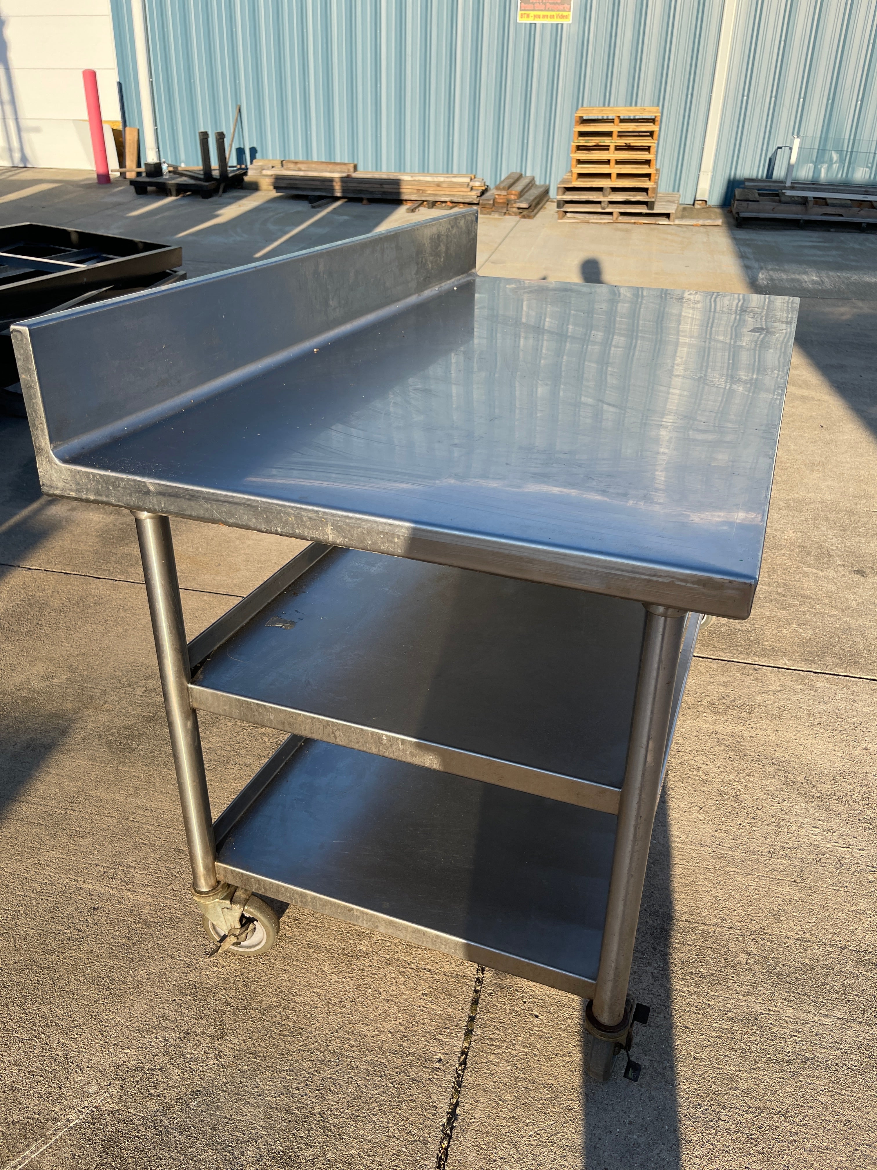 Used 60"x32" Heavy Stainless Table with Shelves, Casters and 6" Backsplash JD - SS325